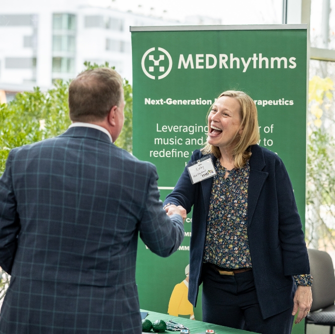 A representative from MedRhythms shaking hands at 25th anniversary event